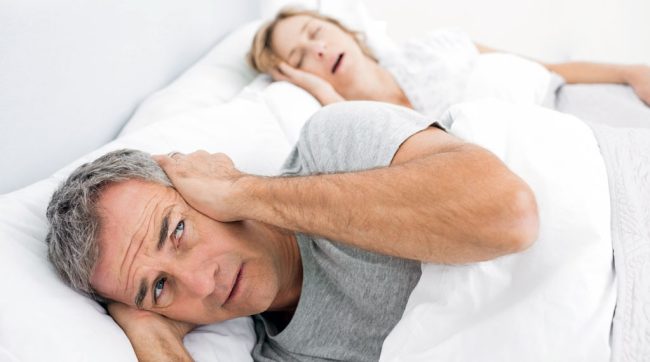 Couple In Bed With Man Bothered By Wife Snoring